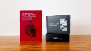 Libro historia del papel moneda en el Perú de César Corrales López, junto a packaging de Crypto Metales.